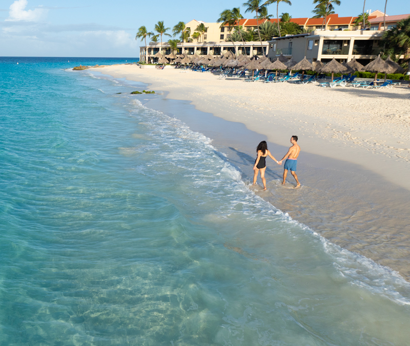 man and woman walking along Divi Aruba All Inclusives beach