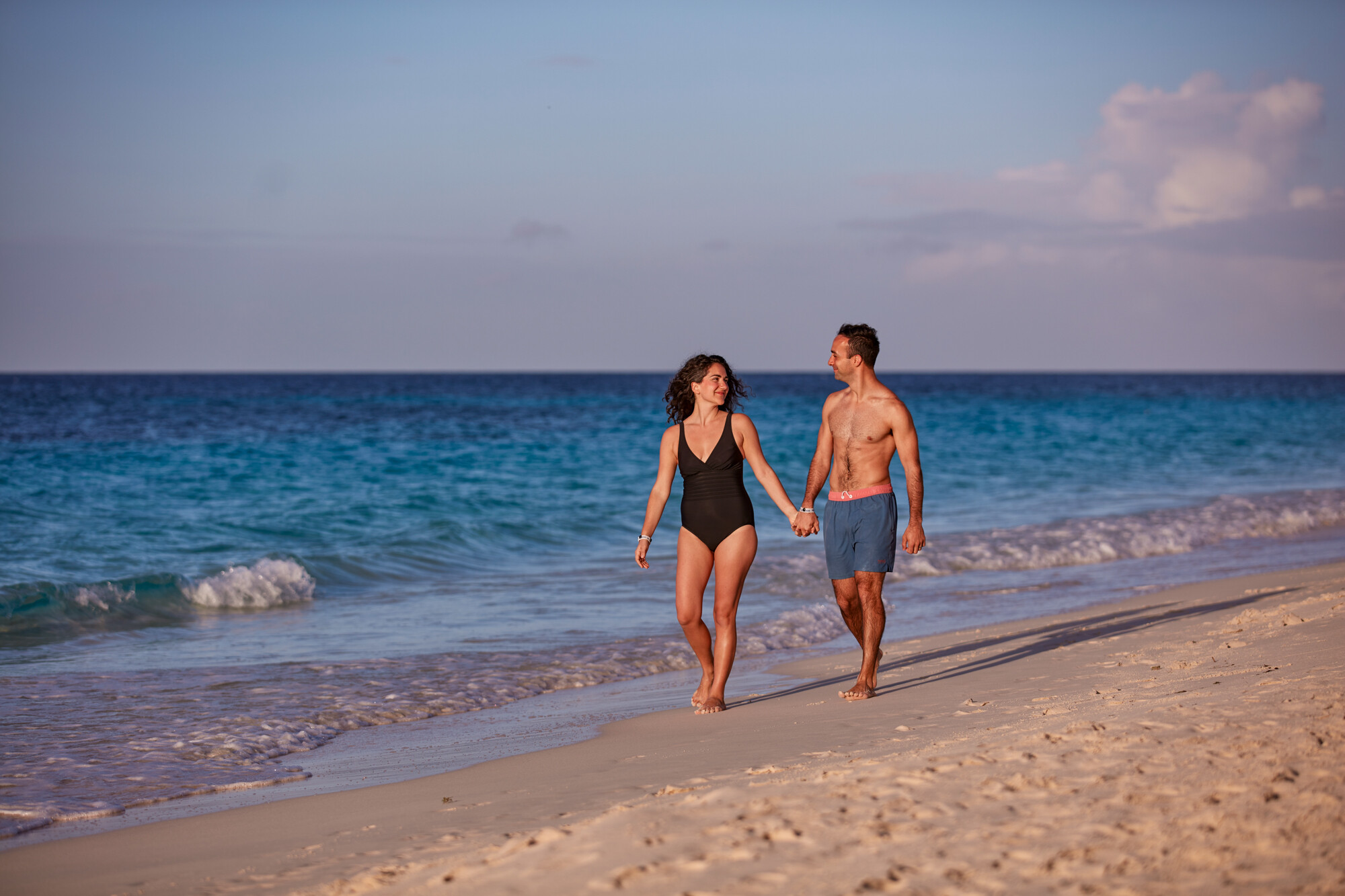 a man and woman holding hands on a beach