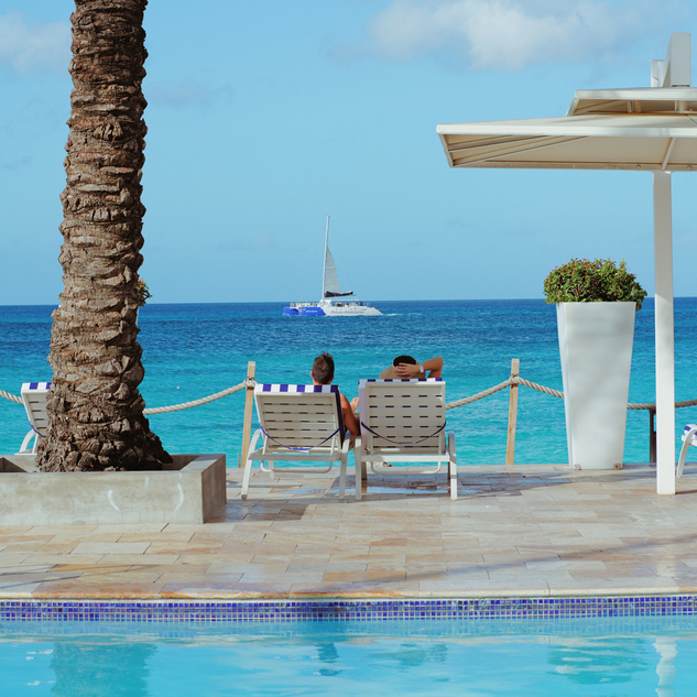 people sitting in lounge chairs by the water